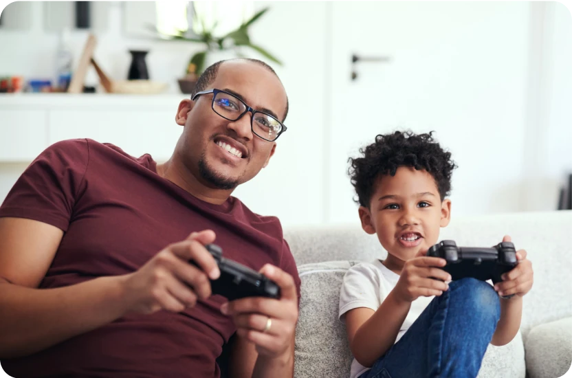 son and father sitting on the couch playing video games